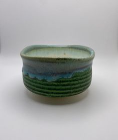 a green and blue bowl sitting on top of a white table