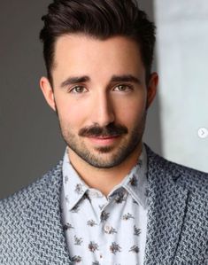 a man with a goatee wearing a suit and tie, looking at the camera