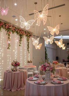 a room filled with lots of tables covered in pink table cloths and butterfly lights