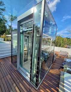 an outdoor room with glass walls and wooden flooring on the outside, surrounded by stairs