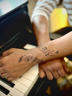 two people holding hands with musical notes on their wrist and piano keyboard in the background