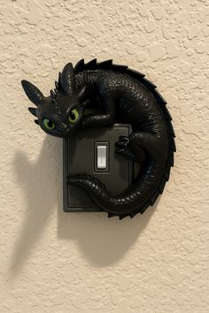 a light switch with a black dragon on it's face and green eyes sitting on the wall