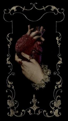 a hand holding a heart in the middle of a frame with filigrees on it