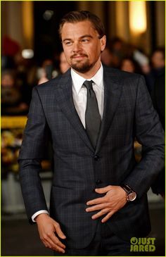 a man in a suit and tie posing for the camera with his hands on his hips