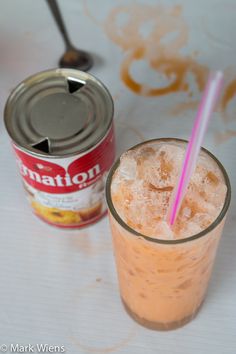 a can of soda next to a drink with a straw in it