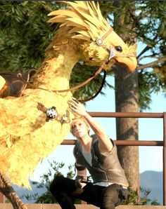 a woman kneeling down next to a yellow bird statue