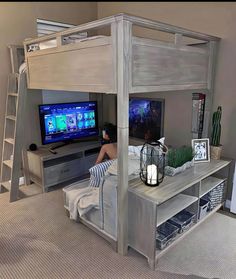 a person sitting in front of a tv on top of a wooden bunk bed next to a desk