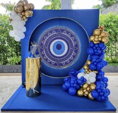 a table with balloons and an evil eye centerpiece on it, in front of a blue backdrop