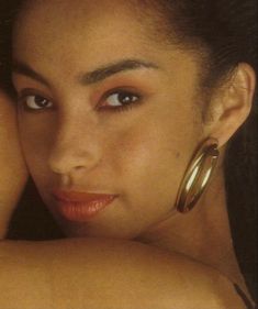 a close up of a woman with large hoop earrings on her head and one arm behind her head