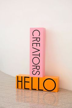 an orange and pink sign sitting on top of a counter next to a white wall