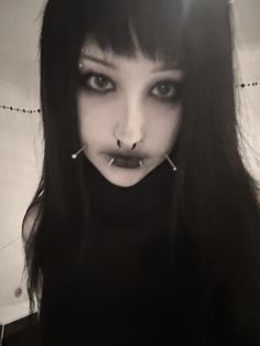 a black and white photo of a woman with piercings on her nose