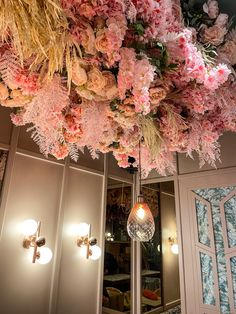 a room filled with lots of pink flowers hanging from the ceiling