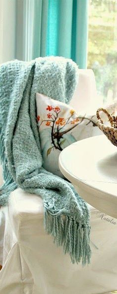 a white table topped with a bowl filled with fruit next to a plate covered in a blanket