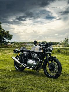 a motorcycle parked in the grass under a cloudy sky