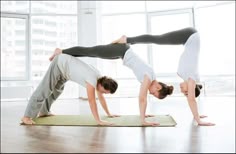 two people doing yoga poses in front of a window