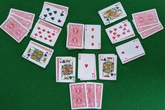 several playing cards laid out on a green surface, with one missing the middle card