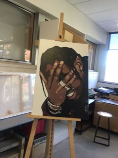 an easel with a painting of a man holding his hand up to his face