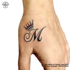 a woman's hand with a crown tattoo on her left thumb and the letter m