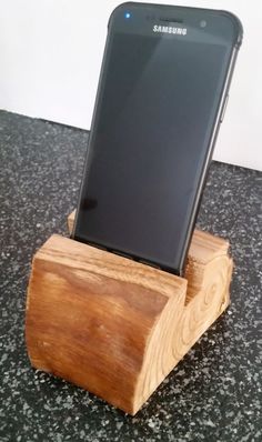 a cell phone is sitting on top of a wooden stand in the shape of a log