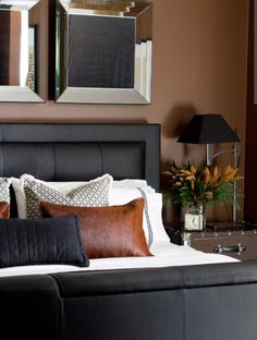 a bed with two mirrors on the wall above it and a black bench in front of it