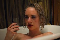 a woman in a bathtub holding a wine glass