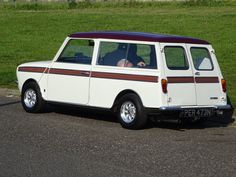 an old white station wagon is parked on the side of the road with grass in the background