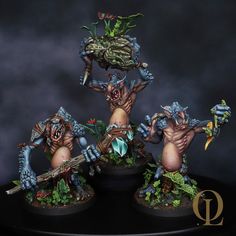 three painted warhammers are posed on a black table with their arms in the air