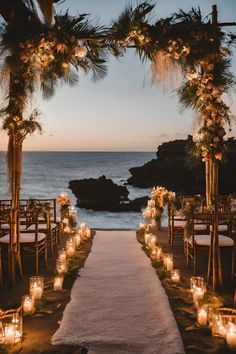 an outdoor wedding setup with candles and greenery on the aisle, overlooking the ocean