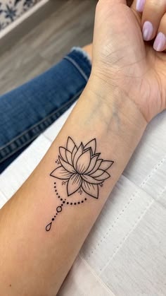 a woman's arm with a tattoo that has a lotus flower on the wrist