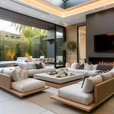 a living room with couches and tables in front of a large glass window that looks out onto the backyard