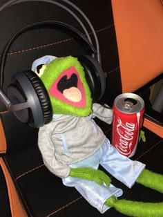 a stuffed animal with headphones on sitting in a chair next to a soda can