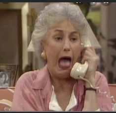 an older woman talking on the phone with her mouth wide open and tongue hanging out