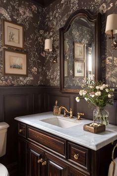 a bathroom with a sink, mirror and toilet in the corner next to wallpaper