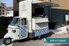 an ice cream truck parked in front of a building with blue tiles on the side