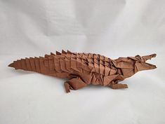 an origami crocodile made out of brown paper