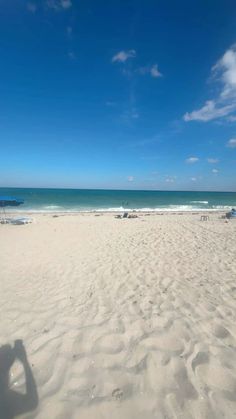 an empty beach with chairs and umbrellas in the sand