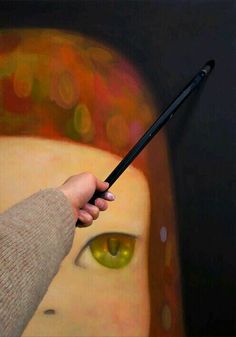 a person holding a paintbrush in front of a painting with an eye on it