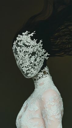 a woman with her hair blowing in the wind, wearing a white dress and veil