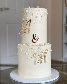 a three tiered wedding cake with pearls and monogramming