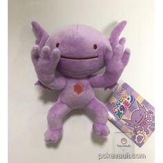a purple stuffed animal with its hands up