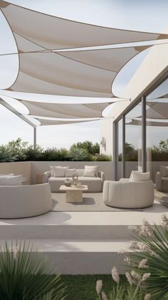 an outdoor living area with couches, tables and white awnings over it