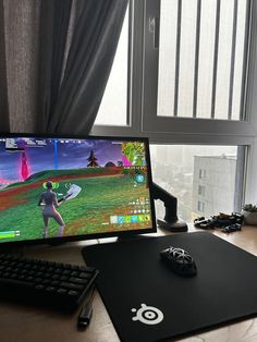 a computer monitor sitting on top of a desk next to a keyboard and mouse with a window in the background