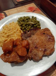 a white plate topped with meat, pasta and peas