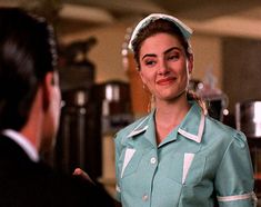 a woman in a green uniform talking to a man