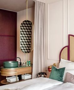 a bedroom with a bed, nightstand and mirror in the corner next to a window