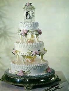 a three tiered wedding cake sitting on top of a table next to a knife and fork