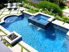 an outdoor swimming pool in the middle of a yard with lounge chairs and fire pit