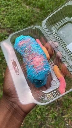 a person holding a plastic container filled with donuts and sprinkled doughnuts