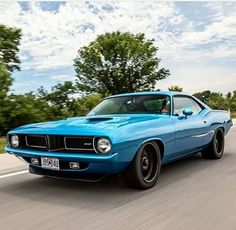 a blue muscle car driving down the road
