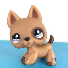 a small toy dog sitting on top of a blue surface with its eyes wide open